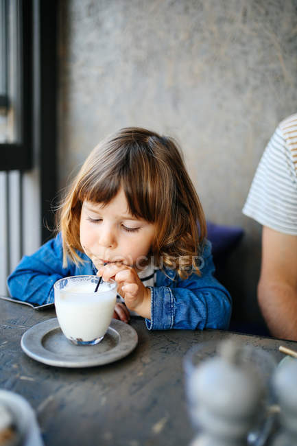 Fille sirotant du lait dans le café — Photo de stock