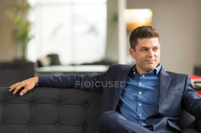 Homme d'affaires confiant assis sur le canapé de bureau — Photo de stock