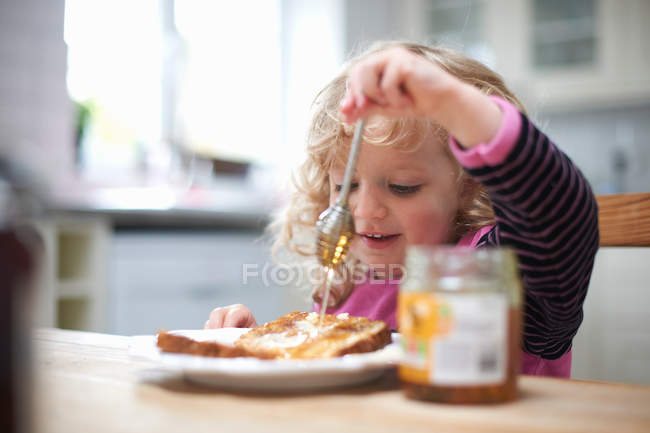 Chica joven sentada en la mesa de la cocina - foto de stock