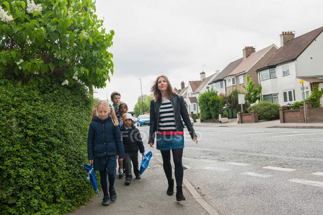 Childminder crianças caminhando para a escola — Fotografia de Stock