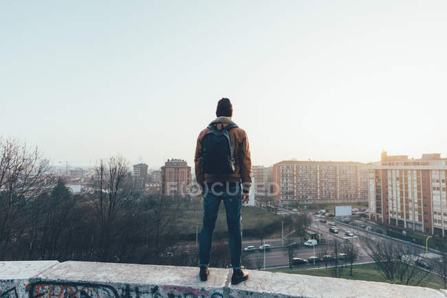 Hipster de pé na parede da cidade olhando para fora — Fotografia de Stock