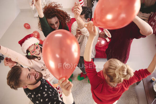 Overhead view of young adult friends dancing with balloons at christmas party — Stock Photo