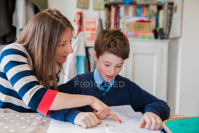 Madre ayudando a hijo con la tarea - foto de stock
