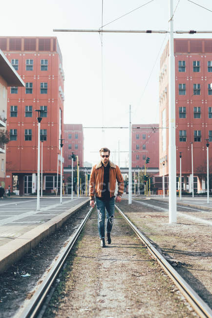 Uomo a piedi lungo le linee del tram della città — Foto stock