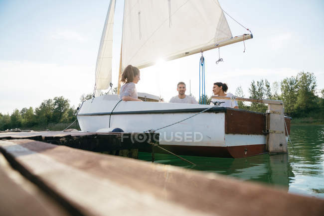 Троє друзів відпочивають на вітрильному човні — стокове фото