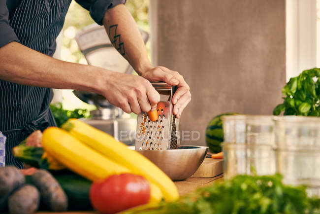 Chef grating carrot — Stock Photo