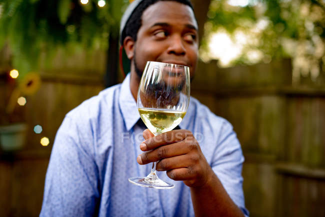 Взрослый мужчина на вечеринке в саду, держит бокал вина — стоковое фото