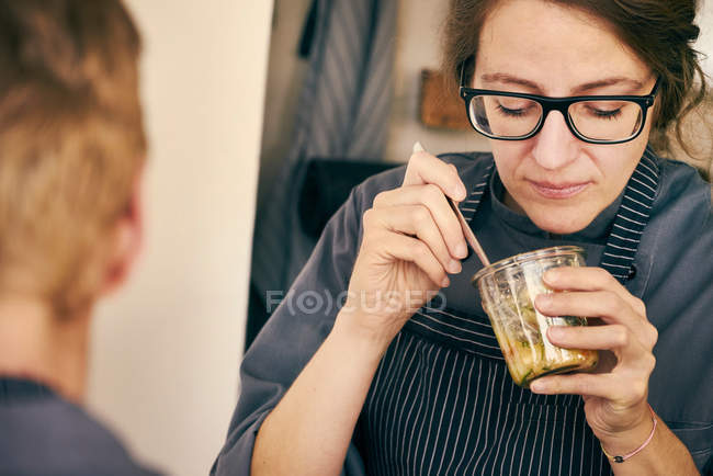 Chef eating food from glass jar — Stock Photo