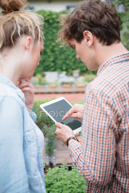 Couple dans le jardin en utilisant une tablette numérique — Photo de stock