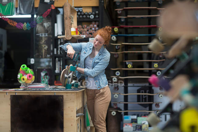 Woman working in skateboard shop — Stock Photo