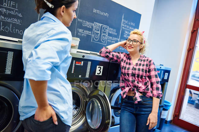 Mujeres hablando por lavadoras - foto de stock