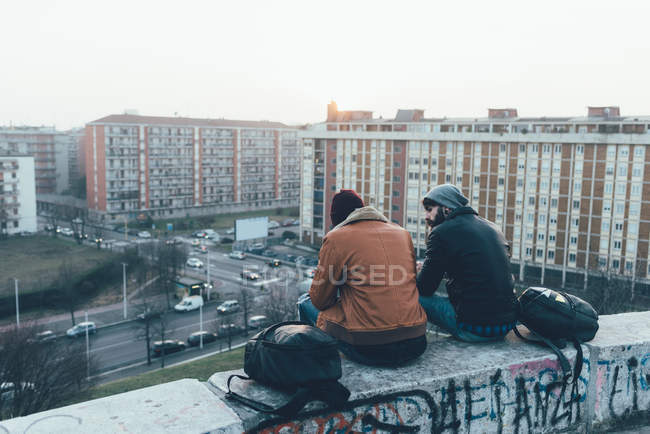 Male hipsters sitting on wall — Stock Photo