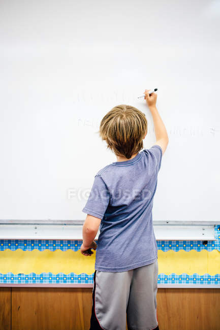 Junge schreibt auf Whiteboard — Stockfoto