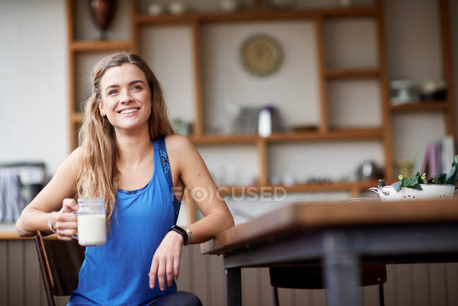 Молода жінка за кухонним столом — стокове фото