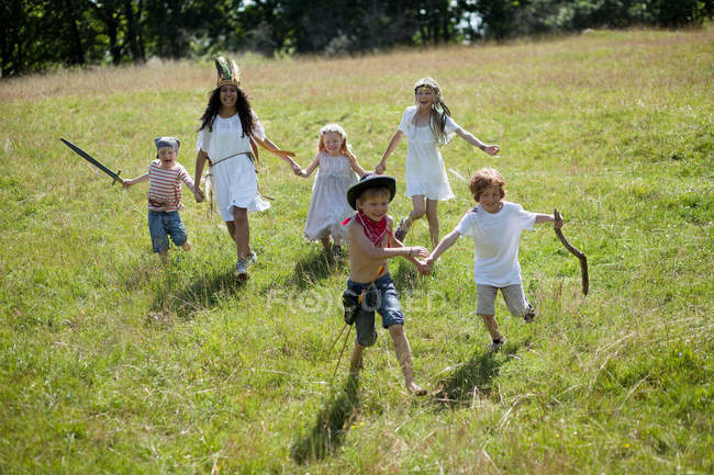 Children in costumes running in field — Stock Photo