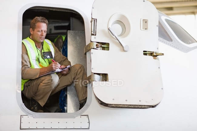 Trabajador aeronáutico comprobando avión - foto de stock