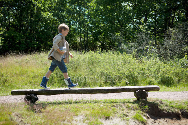Garçon marchant sur banc en bois — Photo de stock