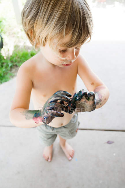 Junge schaut auf schmutzige Hände — Stockfoto