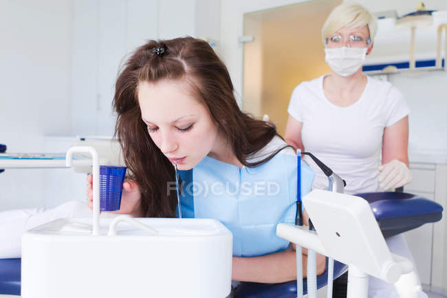 Paciente dental escupiendo en el fregadero - foto de stock