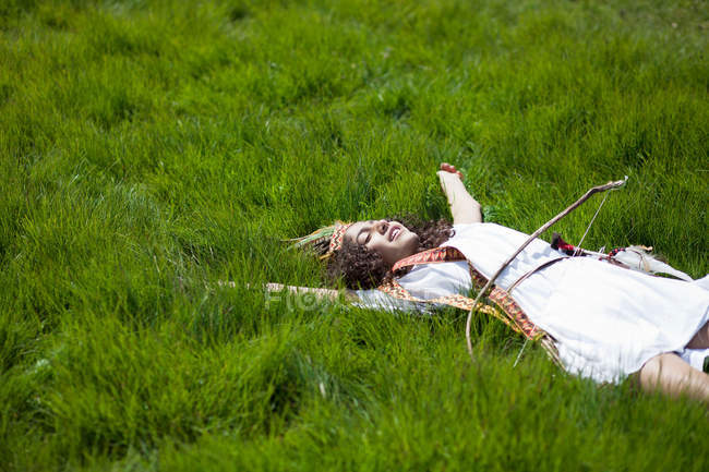 Mädchen im Kostüm liegt im Gras — Stockfoto