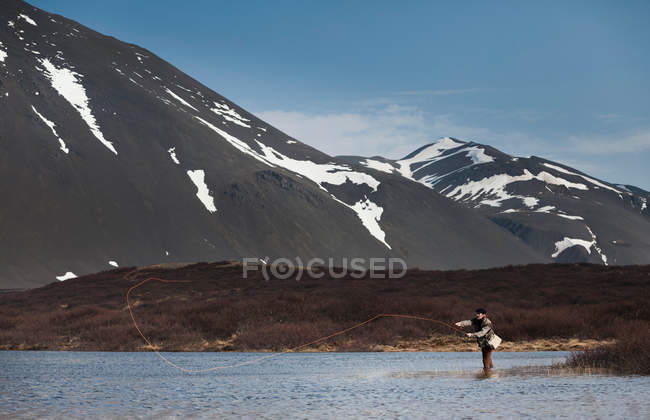 Мужчина рыбачит в тихом озере — стоковое фото
