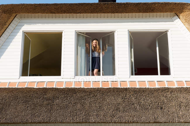 Mädchen steht in geöffnetem Fenster — Stockfoto