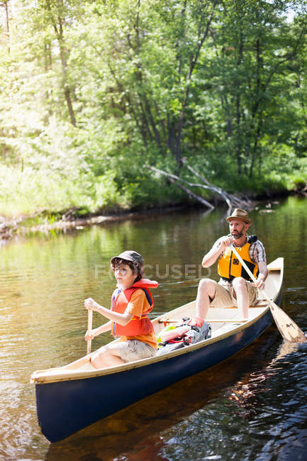 Padre e hijo remando en canoa - foto de stock