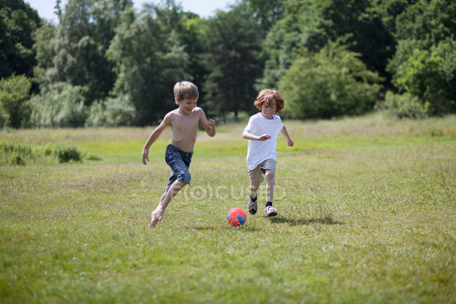Garçons jouant au soccer dans un terrain herbeux — Photo de stock