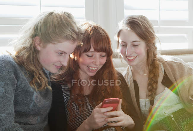 Девушки, использующие сотовый телефон на диване — стоковое фото
