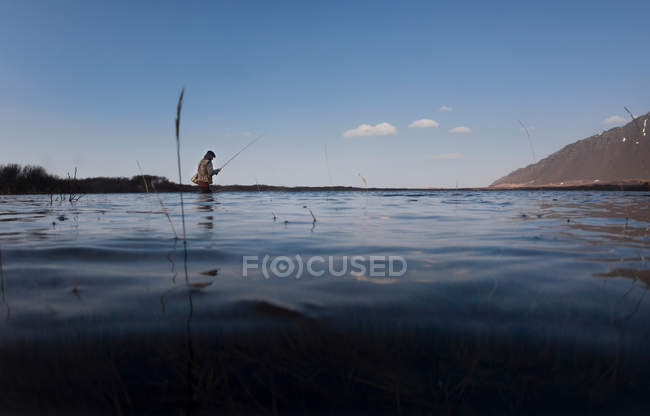 Homme pêche dans encore lac — Photo de stock