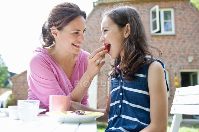 Mãe alimentando filha na mesa de jardim — Fotografia de Stock
