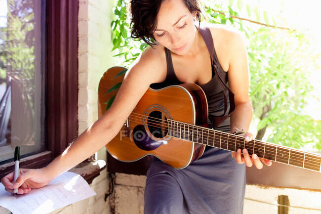 Donna che scrive musica con chitarra — Foto stock