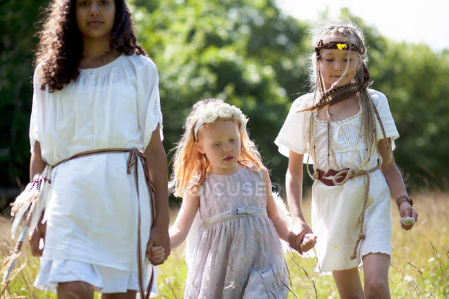 Three girls in costumes walking outdoors — Stock Photo
