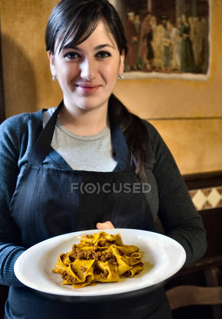 Waitress carrying pasta dish — Stock Photo