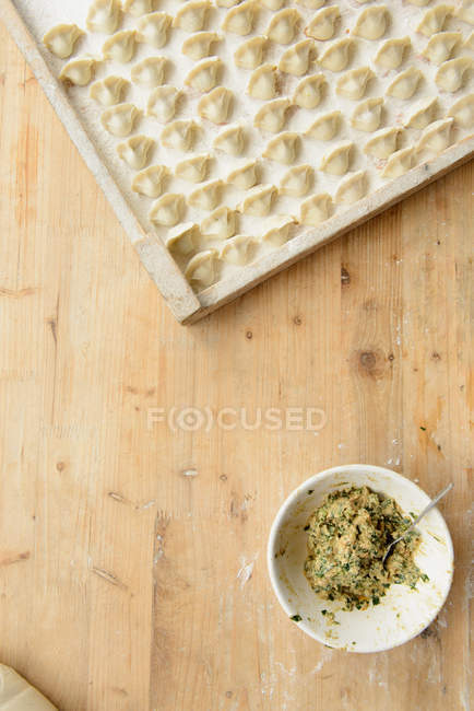 Bowl of filling with tray of dumplings — Stock Photo
