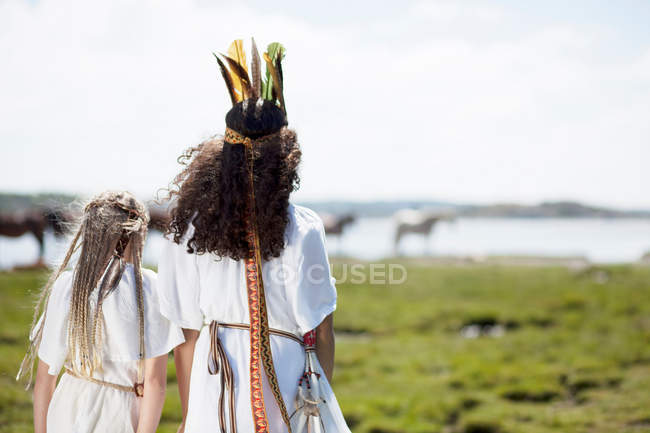 Two girls in costumes on grassy shore — Stock Photo