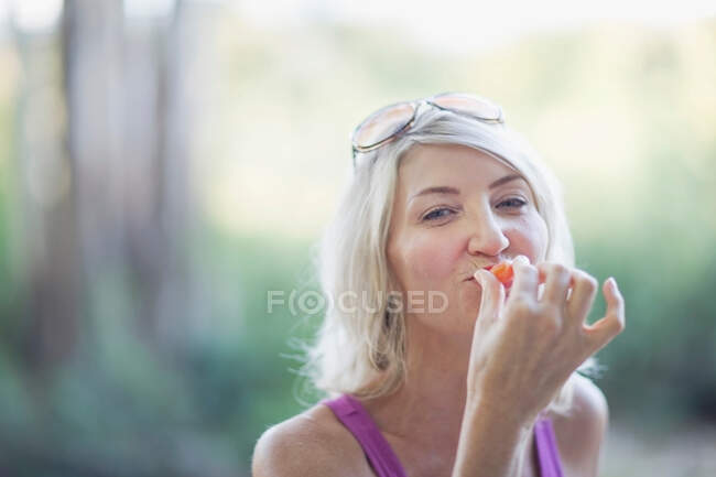Mujer sonriente comiendo al aire libre - foto de stock