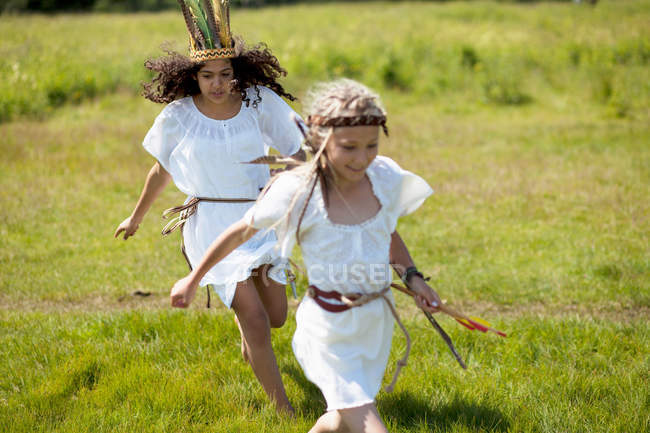 Girls in costumes running in field — Stock Photo