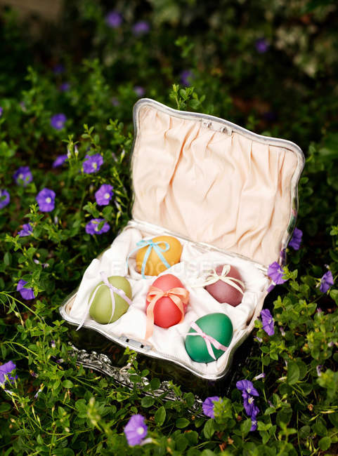 Box with Easter eggs in flowers — Stock Photo