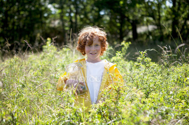 Хлопчик тримає jar у сфері високій траві — стокове фото
