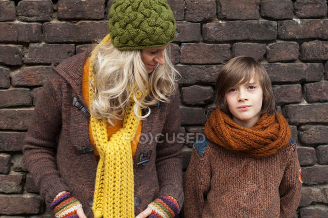 Mother and son standing near brick wall — Stock Photo