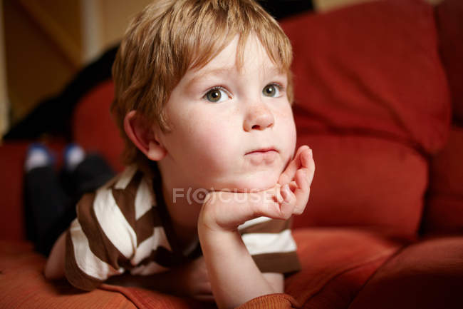 Мальчик лежит на диване в гостиной — стоковое фото