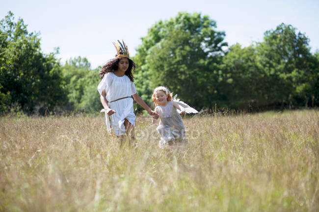 Дівчата в костюмах бігають у полі — стокове фото