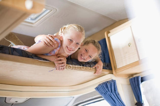 Two smiling girls on shelf in RV — Stock Photo