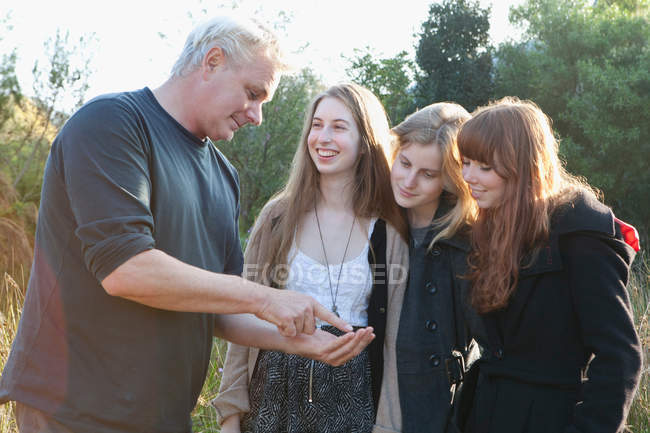 Hombre mostrando algo a chicas adolescentes - foto de stock