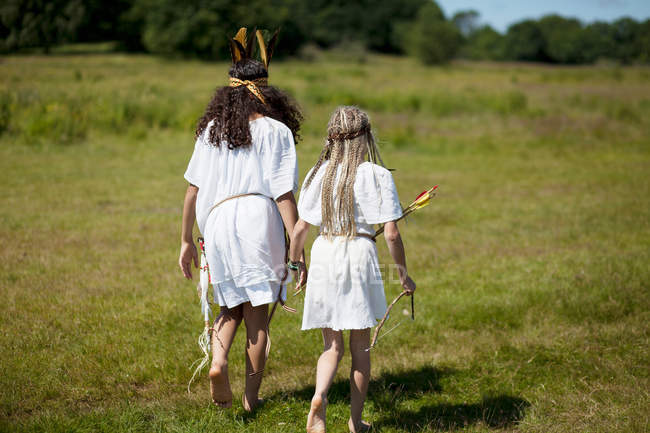 Due ragazze in costume che camminano sul campo — Foto stock