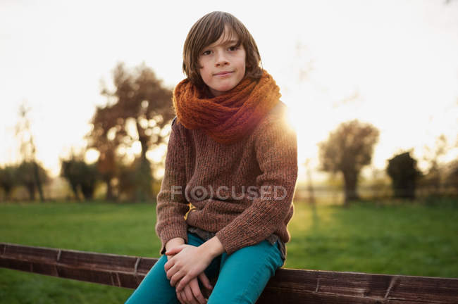 Garçon en écharpe assis sur la clôture — Photo de stock