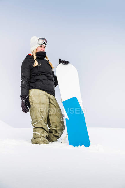 Jeune femme tenant snowboard — Photo de stock