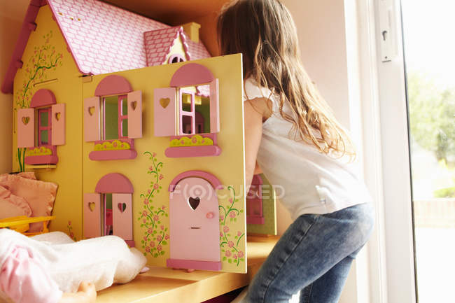 Девушка играет с кукольным домиком в спальне — стоковое фото