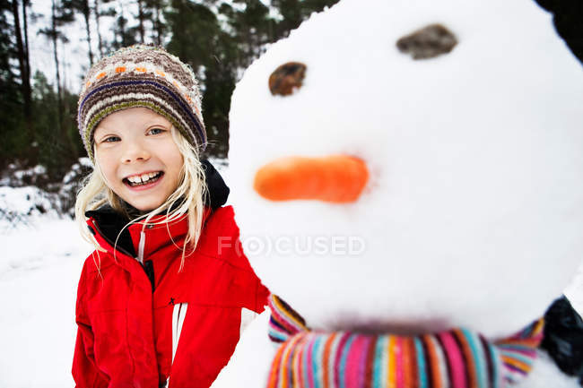 Lächelndes Mädchen spielt mit Schneemann — Stockfoto